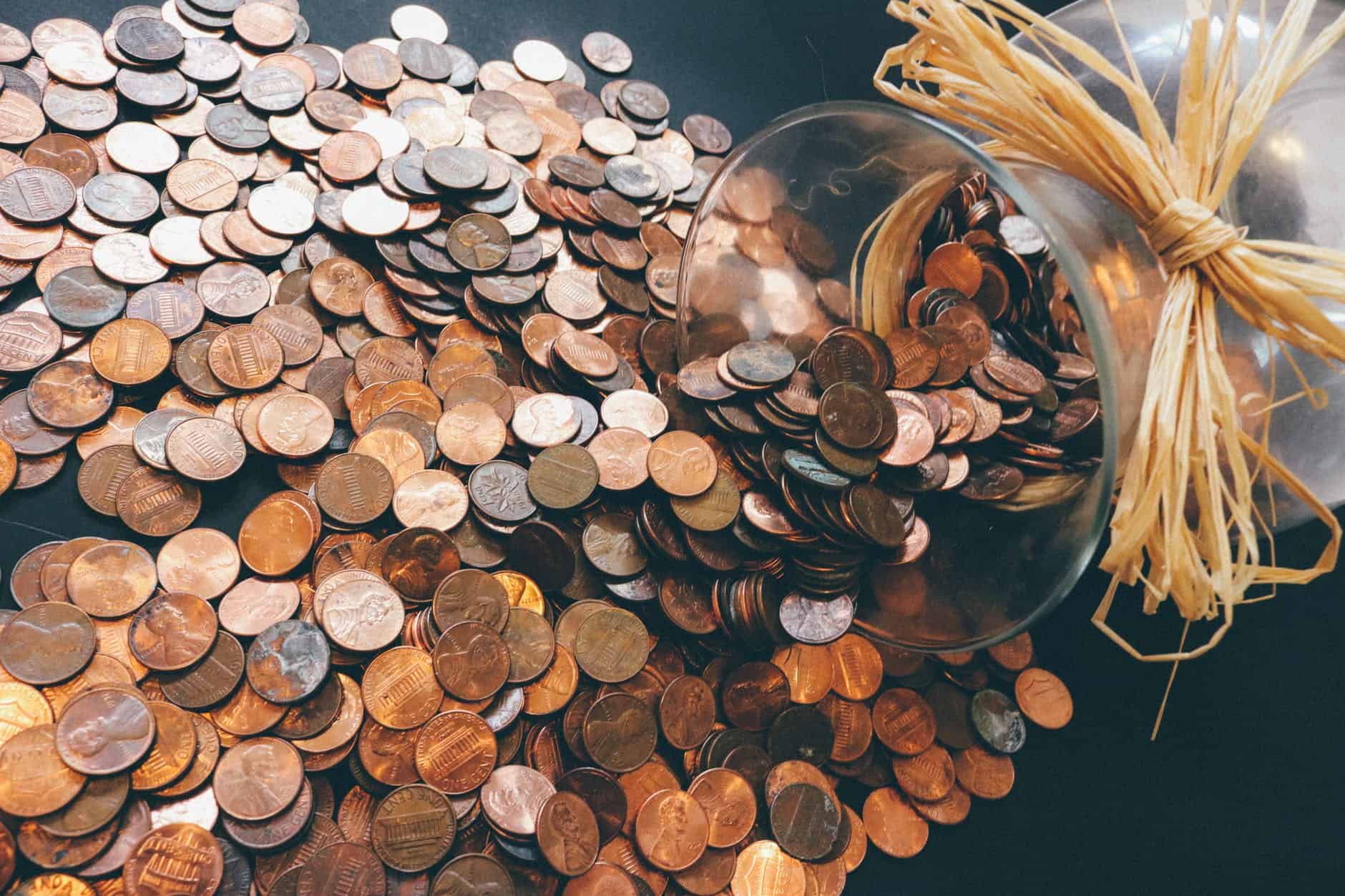 Coins from a glass jar being scattered on the table.