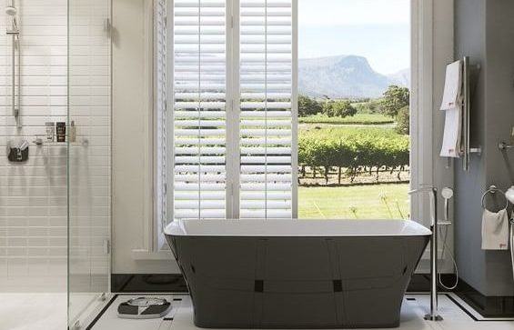 An elegantly-designed bathroom with a bathtub and shower and open doors in the background.