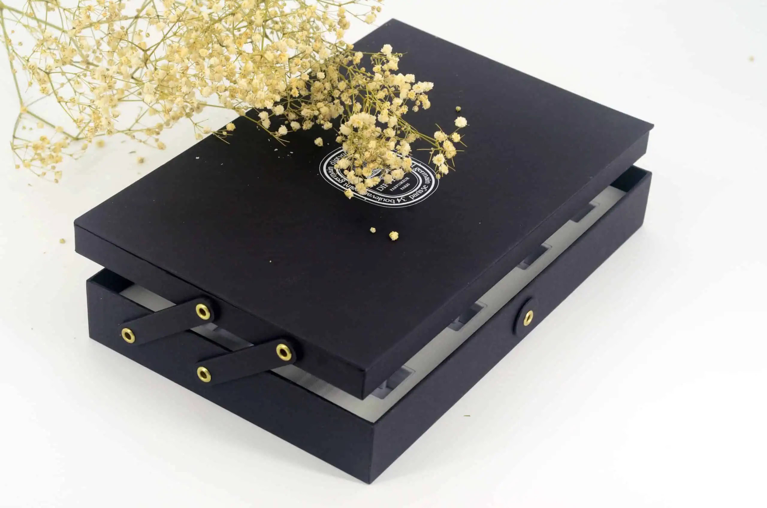 A black decorative box with dried baby's breath on top of it.