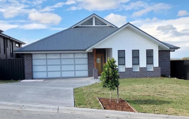 A newly-built house with wide driveway and backyard.