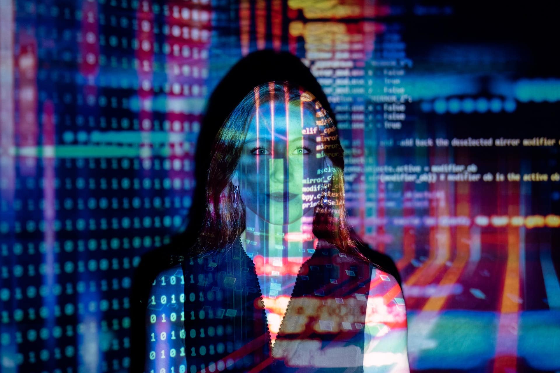 A woman that is in front of a projector beam that is displaying binary code and other programming language.