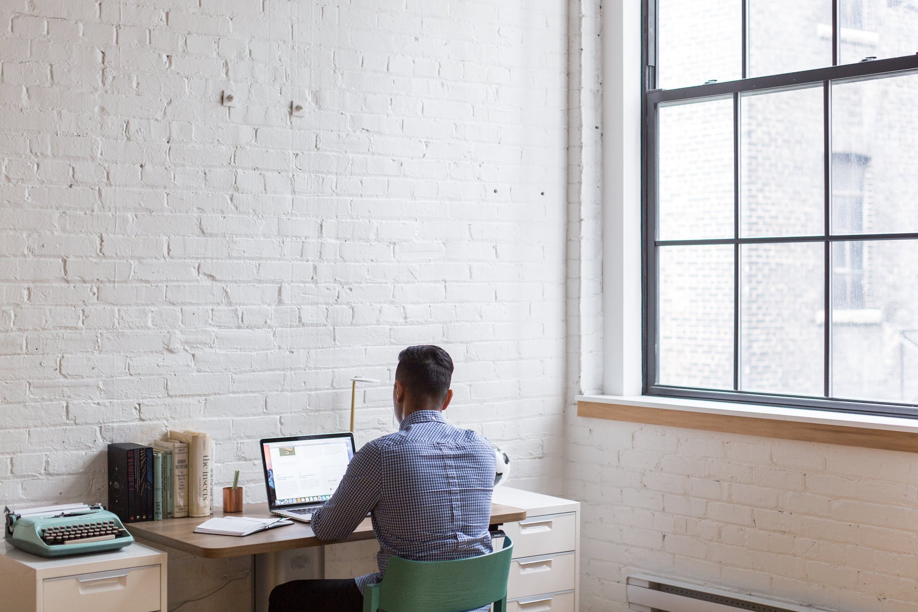 A man on his laptop inside his minimalist, off-white inspired office