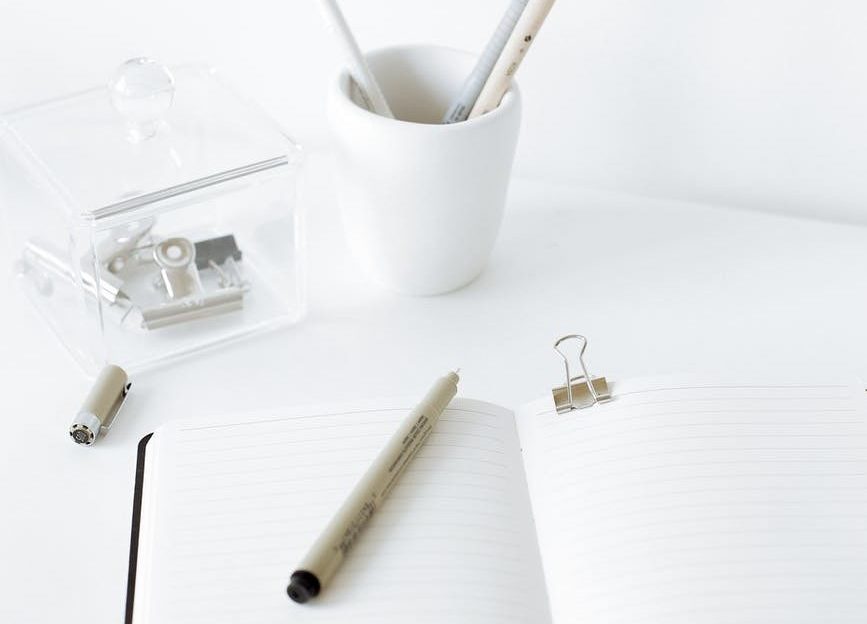 White desk, empty notebook, pen