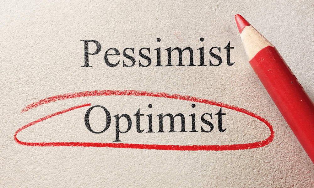 The word pessimist and optimist printed on a wall. Optimist has been circled with a red colouring pencil.