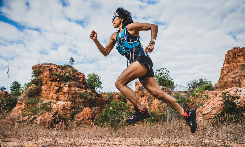 A woman ultra trail marathon runner running through the rock mountain.